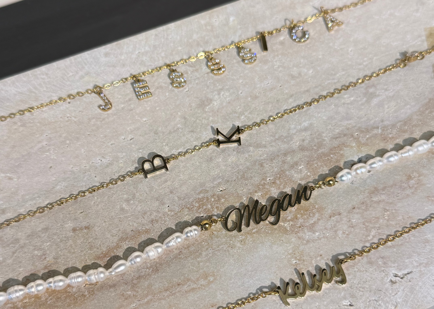 Set of gold necklaces with engraved names on a textured surface